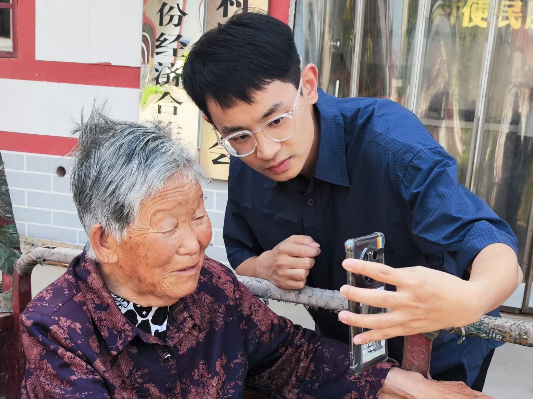 石文喆（右）幫助老人進(jìn)行養(yǎng)老保險認(rèn)證。（瓦崗寨村村委會 供圖）.jpg